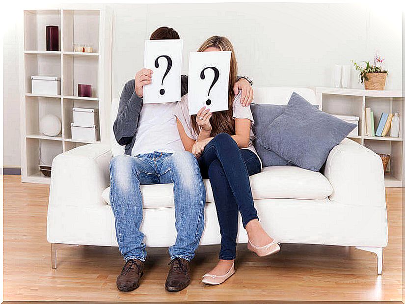 Couple holding a sign with question marks