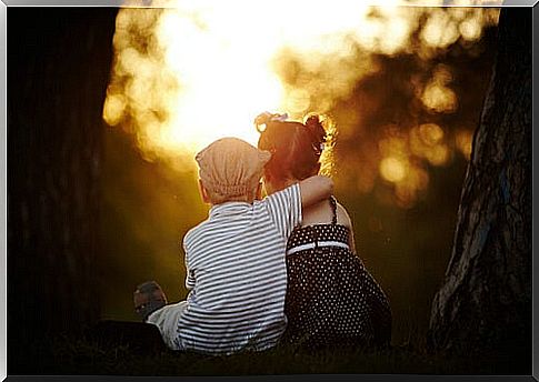 Boy sitting hugging girl at sunset