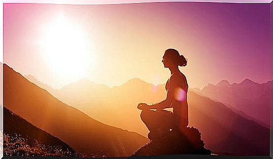 Woman meditating on a mountain at sunrise