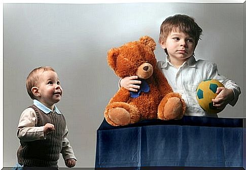 Boy grabbing a bear and a ball without sharing it with his brother