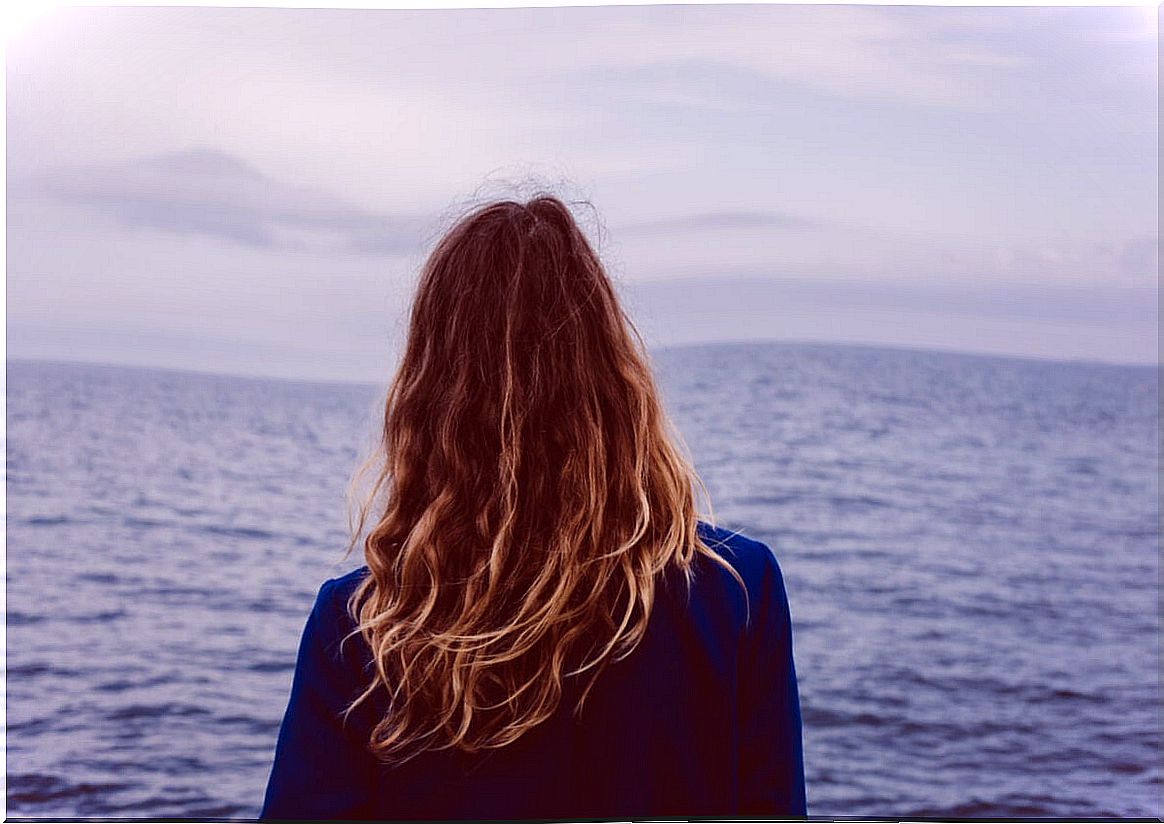 Woman looking at the sea thinking about I have everything but I am not happy