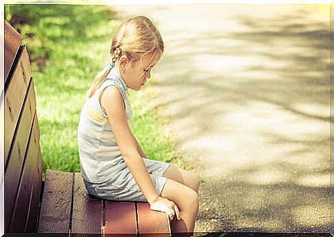 Blond girl sitting on a bench sad