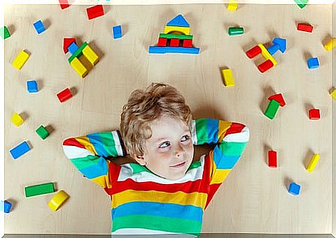 Boy lying on the floor surrounded by pieces of toys