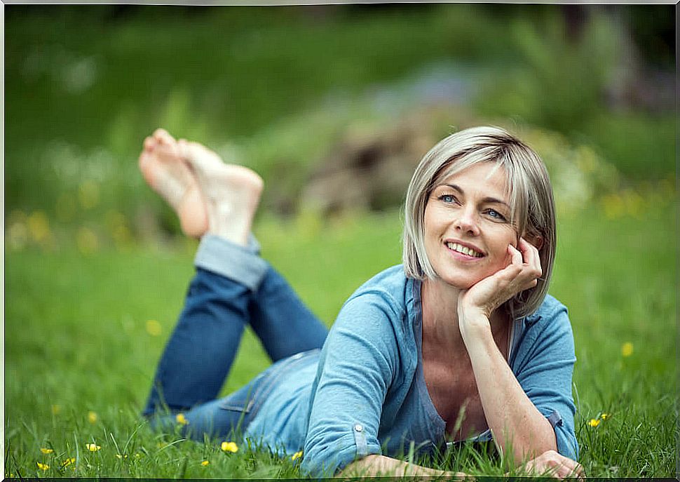 Woman on the grass happy after overcoming the crisis of the 40s