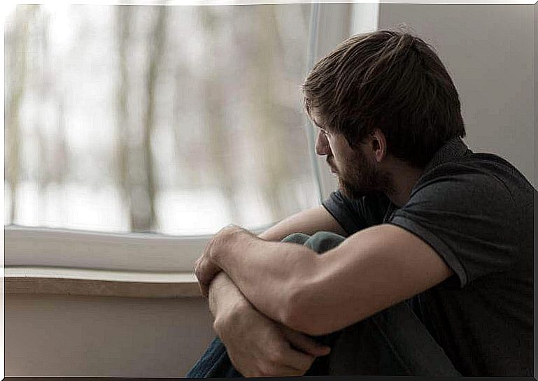 Boy with schizophrenia sitting by the window