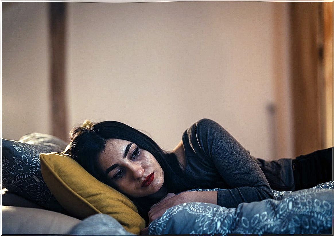 Sad woman in bed thinking about when a friendship betrays us with our partner