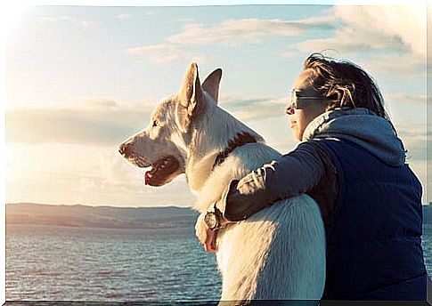 Woman embracing with her dog at sunset 